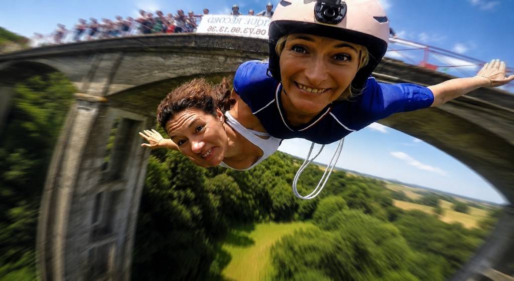 Personnes sautant ensemble durant un saut à l’élastique avec une vue dégagée sur la nature environnante.